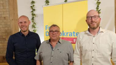 Daniel Derscheid, Alexander Ort und Sebastian Scherer (von links nach rechts) stehen vor einem FDP Banner.